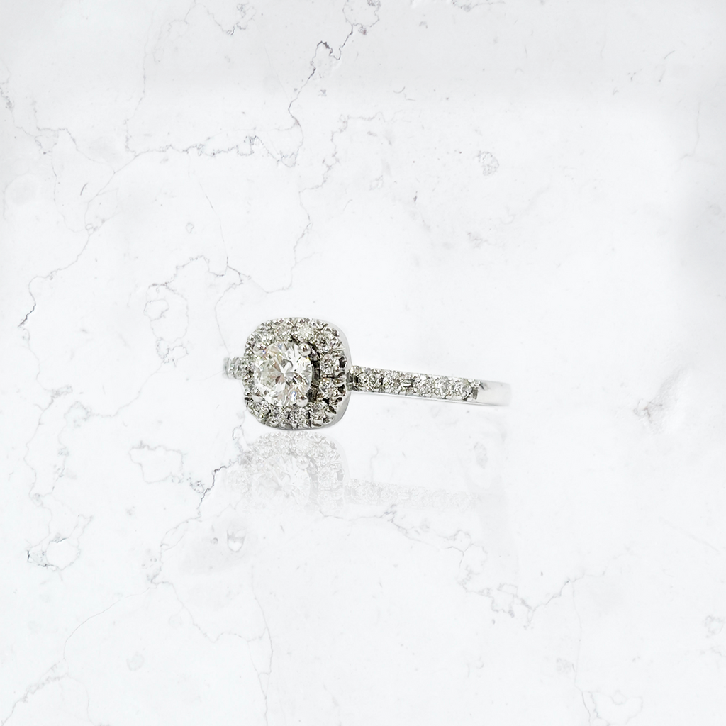 Anillo de compromiso en platino, modelo solitario halo, con diamante corte brillante central de 0,29 cts, rodeado de 12 brillantes de 0,010 cts cada uno, y con 10 brillantes de 0,015 cts cada uno en el cuerpo. 